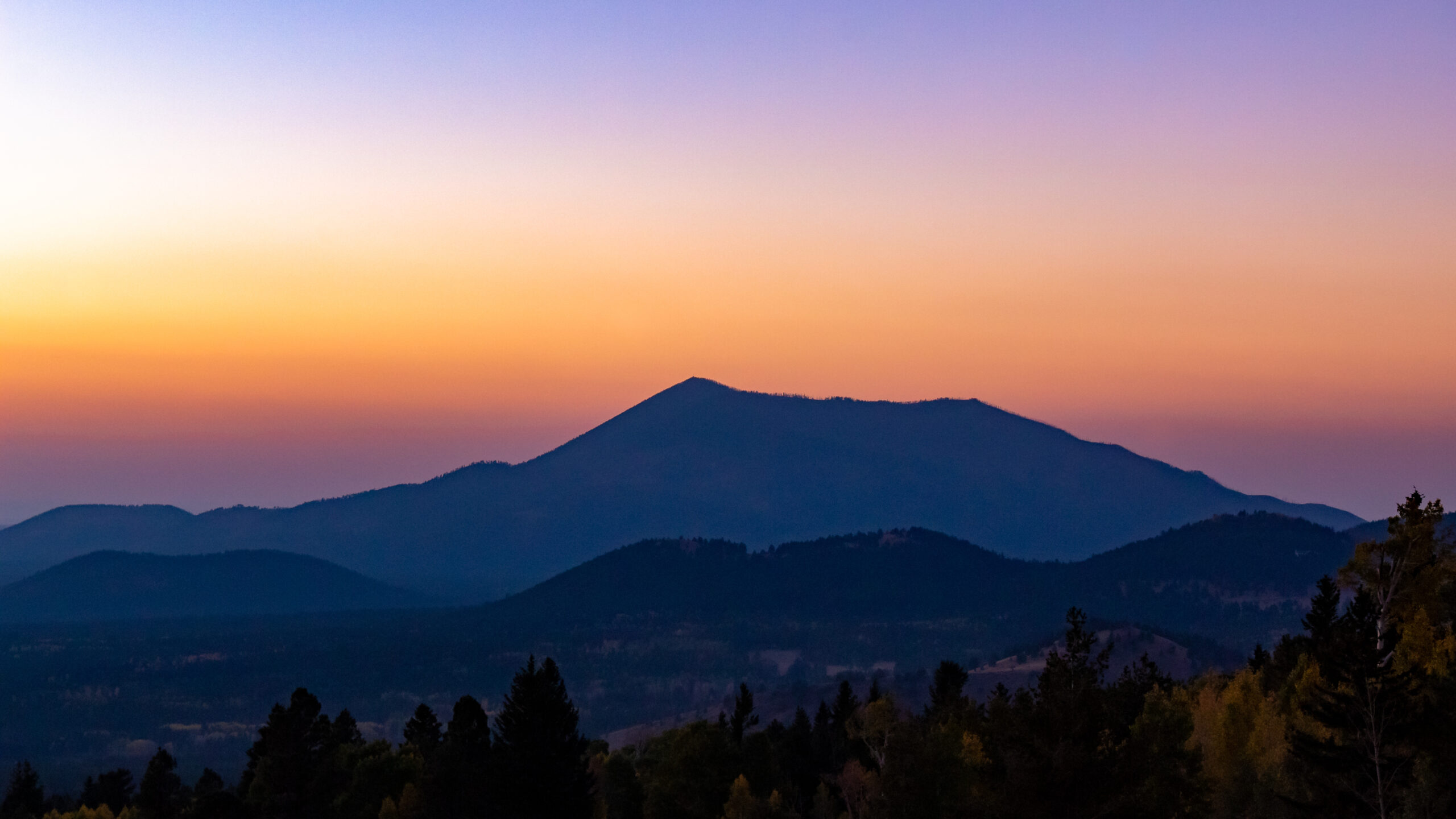 Mountain and volcano silhouette pink golden rolling hills gradient sunset view from top of Humphreys peak